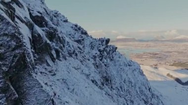 Soğuk bir kış gününde, karla kaplı dağ zirvesi mavi gökyüzü ve kabarık bulutlarla dolu. Kışın Bitihorn Dağı.