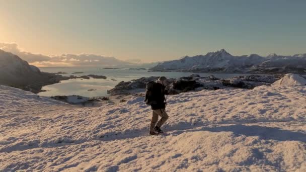 登山コンセプトの山頂に登るバックパック付きのハイカー 雪を歩く男 冬にハイキングする 冒険のトレッキング 自然の概念の人々 エピックサンセットビュー雪山景観 — ストック動画