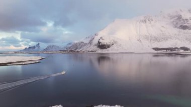 Nefes kesici kuşlar Norveç 'in deniz suyuna yansıyan beyaz karla kaplı yüksek dağlık kayalık tepeleri görüyorlar..