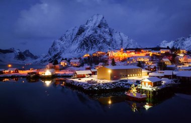 Huzurlu bir kış sahnesi. Işıklarla aydınlatılmış, görkemli karlı dağlara karşı kurulmuş samimi bir kasaba..