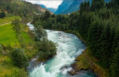 Güzel ve pitoresk bir nehir yavaşça kıvrılıyor yemyeşil tepelerden ve görkemli yüksek dağlardan.