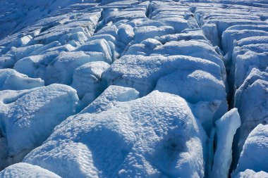 Buzul oluşumlarının bu yakın çekimi, buzlu arazinin eşsiz ve büyüleyici dokularını ve desenlerini sergiliyor.
