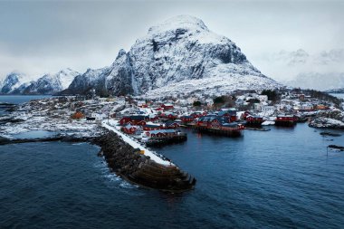 Görkemli dağların ve ışıl ışıl denizin arasına kurulmuş karla kaplı bir köyün nefes kesici manzarasını tecrübe edin.