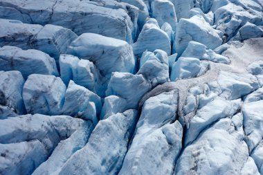 Hava görüntüsü, yüzeyinde karmaşık buz dokuları ve oluşumları olan çarpıcı bir mavi buzulu ortaya çıkarıyor.