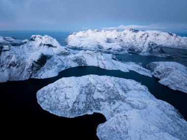 Karanlık suların yanında sersemletici buzlu dağların nefes kesici hava manzarası. Nazik, yumuşak ışıkla aydınlatılıyor.