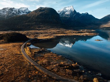 Sakin bir göle yansıyan heybetli dağların çarpıcı manzarası, doğanın güzelliğini yansıtıyor.