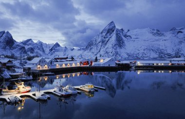Gerçekten çarpıcı bir kış sahnesi, görkemli, karlı dağlarla çevrili sakin bir limanı tasvir eder.