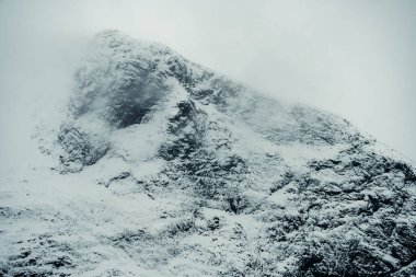 Karla kaplı muhteşem bir dağın nefes kesici ve çarpıcı manzarası, güzel bir şekilde sis ve gizemle örtülü.