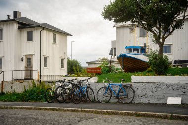 Büyüleyici sahil evlerinin yakınına park edilmiş bisikletlerin ve yemyeşil çimenlerde bir teknenin olduğu nefes kesici manzaralı bir manzara.