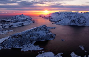 Gün batımında karla kaplı fiyordun nefes kesici hava perspektifi doğanın çarpıcı güzelliğini vurguluyor.