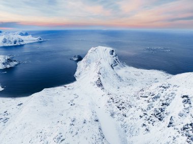Nefes kesici bir hava karla kaplı bir dağ sırası yakalıyor. Güzel bir şekilde okyanusun kenarında, alacakaranlıkta.