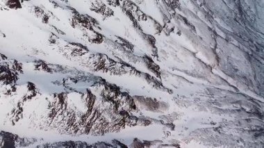 Bu çarpıcı hava fotoğrafı, karla kaplı dağları ve kayalık araziyi gözler önüne seriyor.