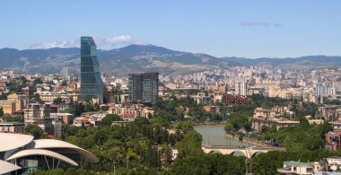 Aerial view on central part of the capital of Georgia Tbilisi Tiflis city with Mtkvari Kura river, two well-known high-rise buildings in the foreground and Vake-Saburtalo neighborhood climbing the