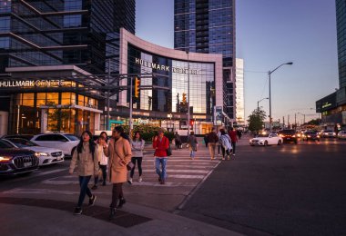 Toronto, Ontario, Canada - 09 23 2022: Pedestrians walking on a crosswalk at the intersection of Younge Street and Sheppard Avenue in North York neighborhood of Toronto city in the evening with last