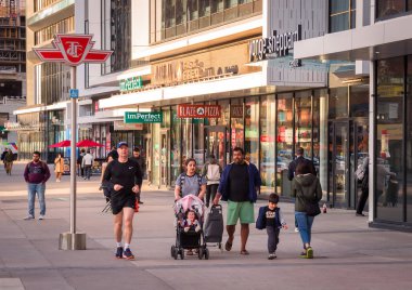Toronto, Ontario, Canada - 10 03 2022: Torontonians on a sidewalk on Younge Street in front of Sheppard Yonge TTC subway station in North York neighborhood of Toronto city in the evening with last sun