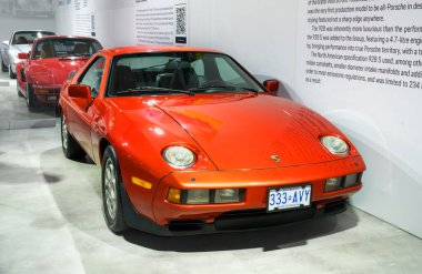 Toronto, Kanada - 02 25 2023: Turuncu metalik Porsche 928 iki kapılı yüksek performanslı büyük turlu spor araba 2023 Kanada Uluslararası Otomobil Fuarı 'nda sergilendi. Porsche 'ler birinci sınıf üretim otomobili.