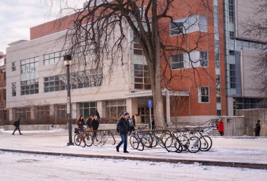 Winnipeg, Manitoba, Kanada - 11: 19 2014: Manitobas Üniversitesi Mühendislik ve Bilgi Teknolojisi Kompleksi binasının önünde yürüyen öğrenciler. Sert kış mevsiminde bile öğrenciler bisiklet kullanır.