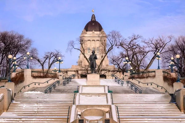 Manitoba Lejyon Binası 'ndaki Assiniboine Nehri kıyısından kış manzaralı Winnipeg, Manitoba, Kanada' da Louis Riel heykeli. 1996 yılında oluşturulan 3,5 metre yüksekliğindeki heykel, Riel 'in