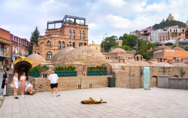 Tiflis, Gürcistan - 08: 24 2024: Gürcistan 'ın Eski Tiflis ilçesinin Abanotubani ilçesindeki eski bir kükürt hamamının önünde köpekli turistler.