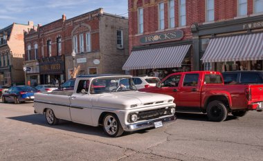 Port Perry, Ontario, Kanada - 2024 10 05: 1960-1966 klasik Chevrolet C10 kamyonu Queen Caddesi boyunca çeşitli küçük işletmelerin büyük mağazaları olan iki katlı tuğla binaların önünde sürüyor.