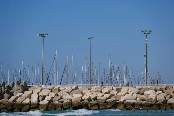 Beton dalga kırıcı tetrapodlar açık mavi gökyüzünün altında kıyı şeridini güçlü deniz dalgalarından koruyor..