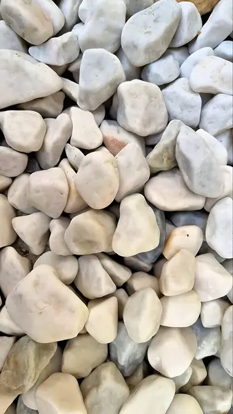 Bir yığın pürüzsüz beyaz taşın yakın çekimi. Ses tonundaki doğal doku ve ince varyasyonlar onu arka plan ya da tasarım elementleri için ideal kılar..