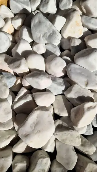 Bir yığın pürüzsüz beyaz taşın yakın çekimi. Ses tonundaki doğal doku ve ince varyasyonlar onu arka plan ya da tasarım elementleri için ideal kılar..