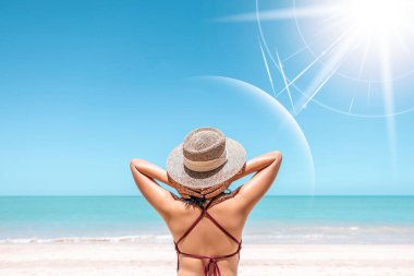 Asyalı manken kırmızı mayo ve hasır şapka giyer plaj manzaralı sıcak bir günde, güneş ve ultraviyole ışınlar güzel kadının koruyucu tabakasına çarpar. Spa, güneş kremi, kozmetik, sağlık konsepti.