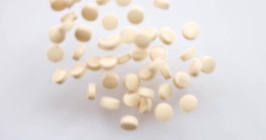 Yakın plan Top View - bir grup hap ve hafif turuncu uçakla stüdyoda kameraya doğru uçuyor. Sağlık için vitamin takviyesi. Uyuşturucu bağımlılığı. 4k çözünürlüğü.