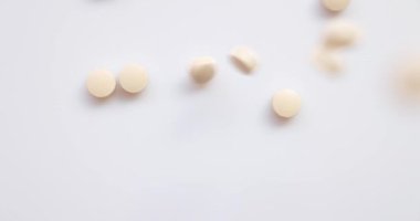 Yakın plan Top View - bir grup hap ve hafif turuncu uçakla stüdyoda kameraya doğru uçuyor. Sağlık için vitamin takviyesi. Uyuşturucu bağımlılığı. 4k çözünürlüğü.