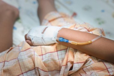 Hastanedeki çocuk elini normal serum fizyolojik enfüzyonuyla kapat çünkü grip A. Hastane koğuşundaki bir hastanın eli. Tedavi, acil durum, tıbbi, kemoterapi, hastalık konsepti.