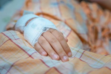 Hastanedeki çocuk elini normal serum fizyolojik enfüzyonuyla kapat çünkü grip A. Hastane koğuşundaki bir hastanın eli. Tedavi, acil durum, tıbbi, kemoterapi, hastalık konsepti.