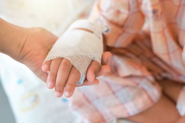 Anne, hastane koğuşunda hasta çocuğunun elini tutuyor. Hastanede serum fizyolojik verildi çünkü grip A 'ymış. Tedavi, acil durum, tıbbi, kemoterapi, hastalık konsepti.