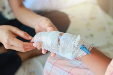 Anne, hastane koğuşunda hasta çocuğunun elini tutuyor. Hastanede serum fizyolojik verildi çünkü grip A 'ymış. Tedavi, acil durum, tıbbi, kemoterapi, hastalık konsepti.