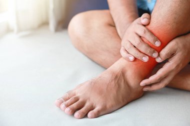 Bir adam ayak bileğini incitti ve o şişmiş ve kırmızıydı. Ağrı nedenleri arasında ayak bileği burkulması, gut, romatizma, ofis sendromu, uyuşukluk ve kramp belirtileri var. Sağlık hizmetleri tıbbi konsepti.