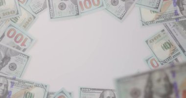 Bir kaç banknotla çevrili beyaz bir arka plana yerleştirilmiş 100 dolarlık banknotu ele alalım. Amerika Birleşik Devletleri Finans. Bankacılık, nakit para, tasarruf ve fiat para kavramları. Para Mockup. 4K VDO.