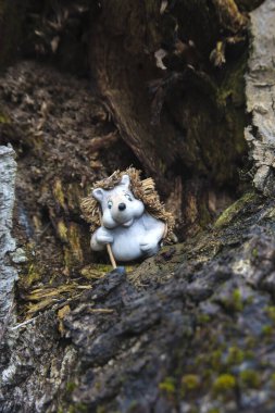 A figurine of a traveling hedgehog against the background of an old, dry and rotten tree. A good composition for creating greeting cards for those who love travel and adventure.