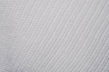 Bu yakın çekim beyaz bir süveterin karmaşık örgü desenini gösteriyor. Kumaş dokusu ve ayrıntılar açıkça görülüyor..