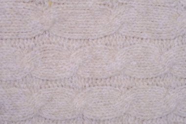 Örgü sürecinin yarattığı karmaşık desenleri ve dokuları gösteren beyaz örülü battaniyenin detaylı bir görüntüsü..