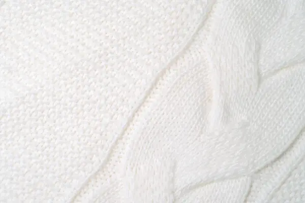 Detailed close up view of a white blanket, showing the texture and fabric of the material with a focus on its color and patterns.