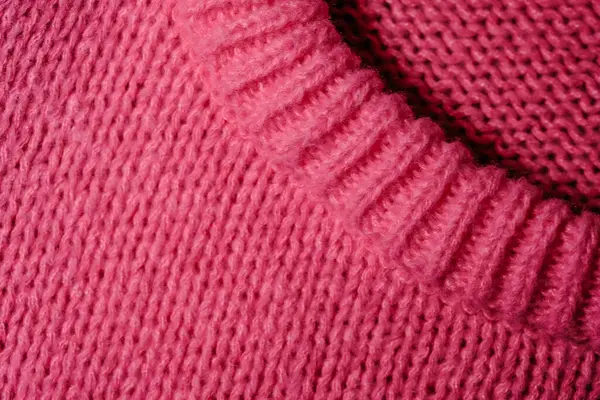 A detailed view of a pink knitted sweater, showcasing its intricate stitches and soft texture.