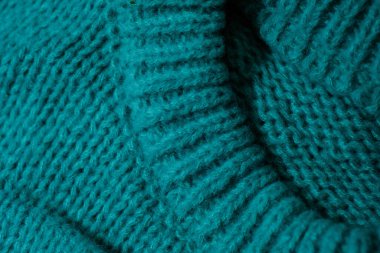 Canlı mavi bir süveterin detaylı bir görüntüsü, kumaşın dokusunu ve dokusunu yakından gösteriyor..