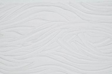 Karmaşık dalgalı çizgilerden oluşan beyaz bir duvarın detaylı görüntüsü görsel dinamik bir desen oluşturuyor..