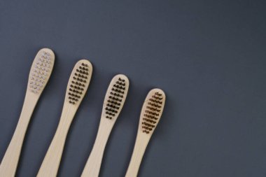 Üç diş fırçası düzgün bir sıra halinde dizilmiş, renkli kıllarını ve saplarını düz bir arkaplanda sergiliyorlar..