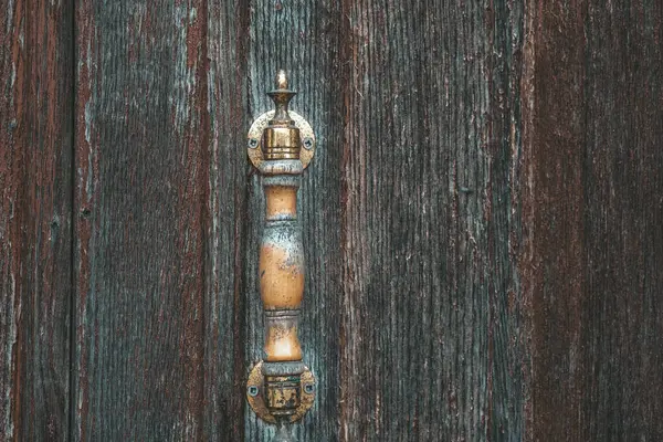 A metallic door handle affixed to a solid wooden door, showcasing a blend of functionality and aesthetics in a simple household entrance.