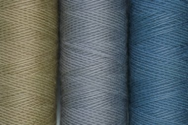 Bir yüzeyde farklı renklerde dizilmiş dört iplik makarası.