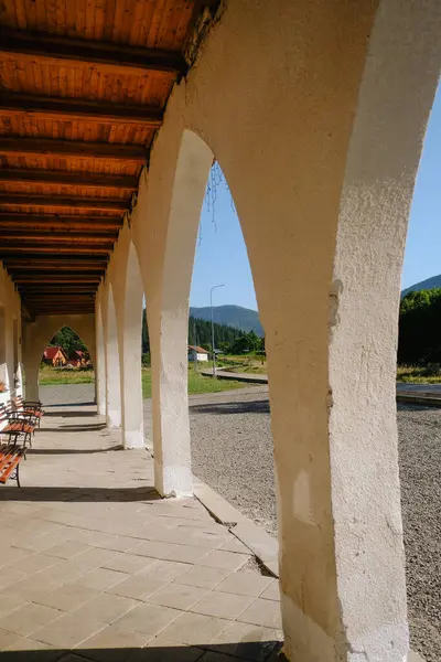 stock image The shaded walkway features elegant arches and wooden ceiling beams, providing a serene atmosphere in a rural setting.