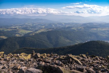 Nefes kesen bir manzara, önplanda kayalık arazi ve berrak bir gökyüzü altında kayan tepeleri ve uzak dağları gözler önüne serer..