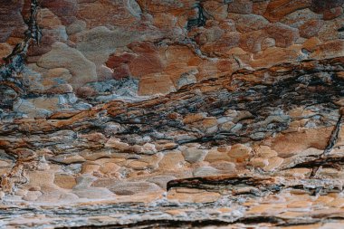 Çok renkli kaya oluşumları, sabahın ilk ışıklarıyla aydınlatılan güzel bir kanyonda eşsiz doku ve desenler ortaya koyuyor..