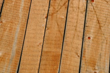 Görüntü, çaprazlama dizilmiş ahşap tahtaların detaylı bir perspektifini içeriyor. Yumuşak gün ışığı altında doğal dokularını ve sıcak renklerini vurguluyorlar..